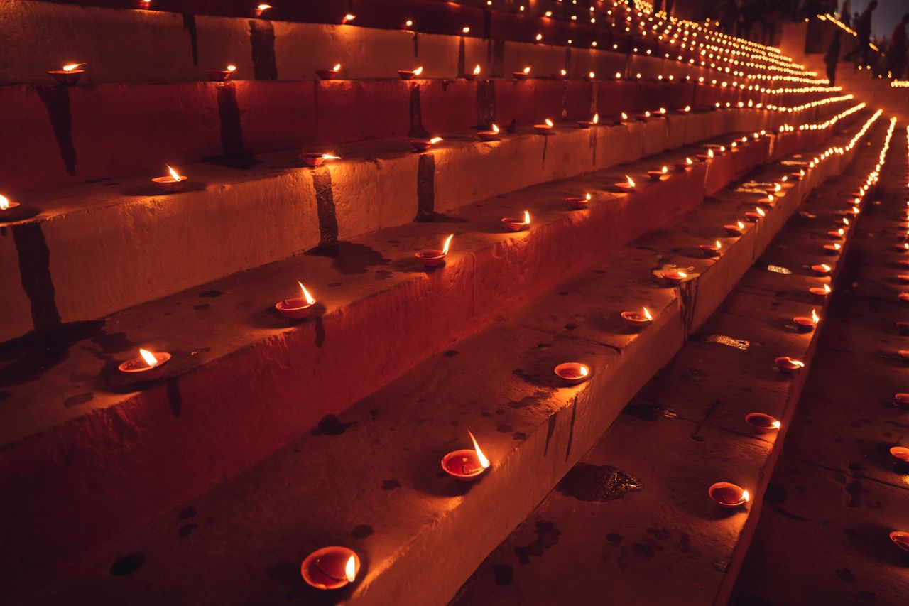 Rows of lit clay diyas glowing at night